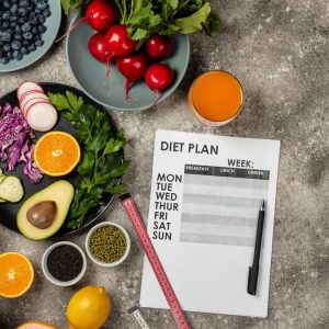 Platoul de slăbire: de ce se oprește cântarul și ce faci concret 1 O fișă de plan alimentar și un centimetru de croitorie, înconjurate de legume, fructe de pădure și avocado