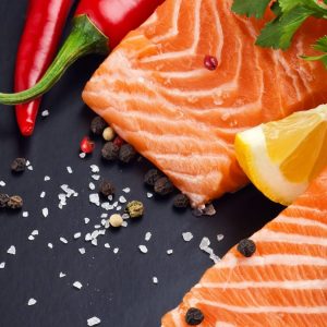 Vitamina D în România: de ce ești deficitar din septembrie până în aprilie 1 Două file de somon crud pe o placă neagră, cu felie de lămâie, pătrunjel, ardei iute, sare grunjoasă și boabe de piper